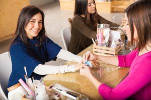 Woman smiling while getting a manicure at a modern, clean nail salon in Toronto, featuring nail technician and professional products. Nail salons in Toronto.