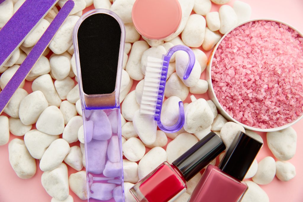 Nail care products on pebbles, colorful polish in bottles on pink background, nobody. Healthcare procedures concept, fashion cosmetic, manicure and pedicure tools, fingernail varnish