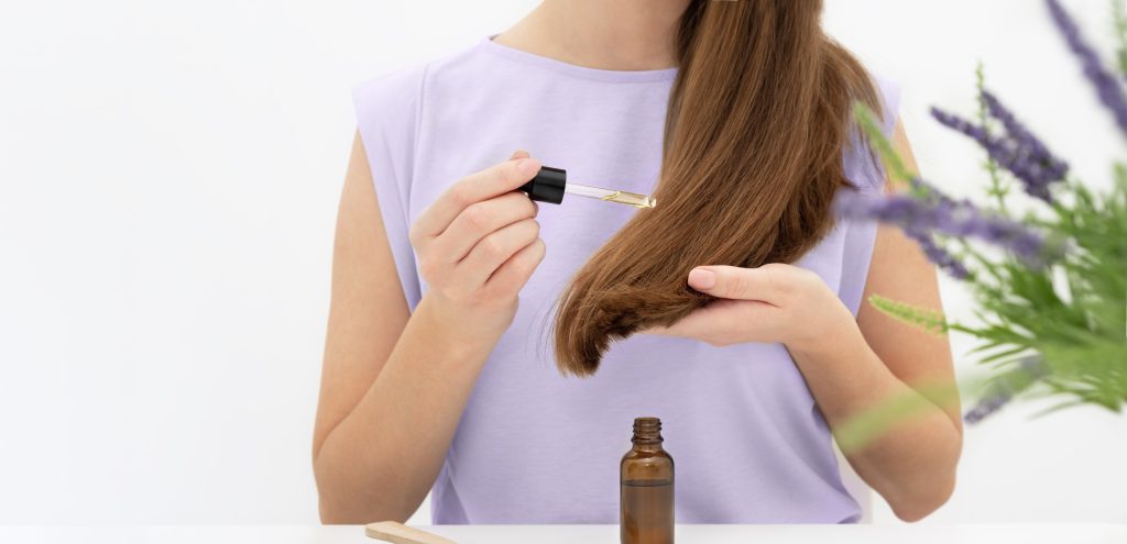 Woman applying hair serum on her hair. Hair treatment. 
