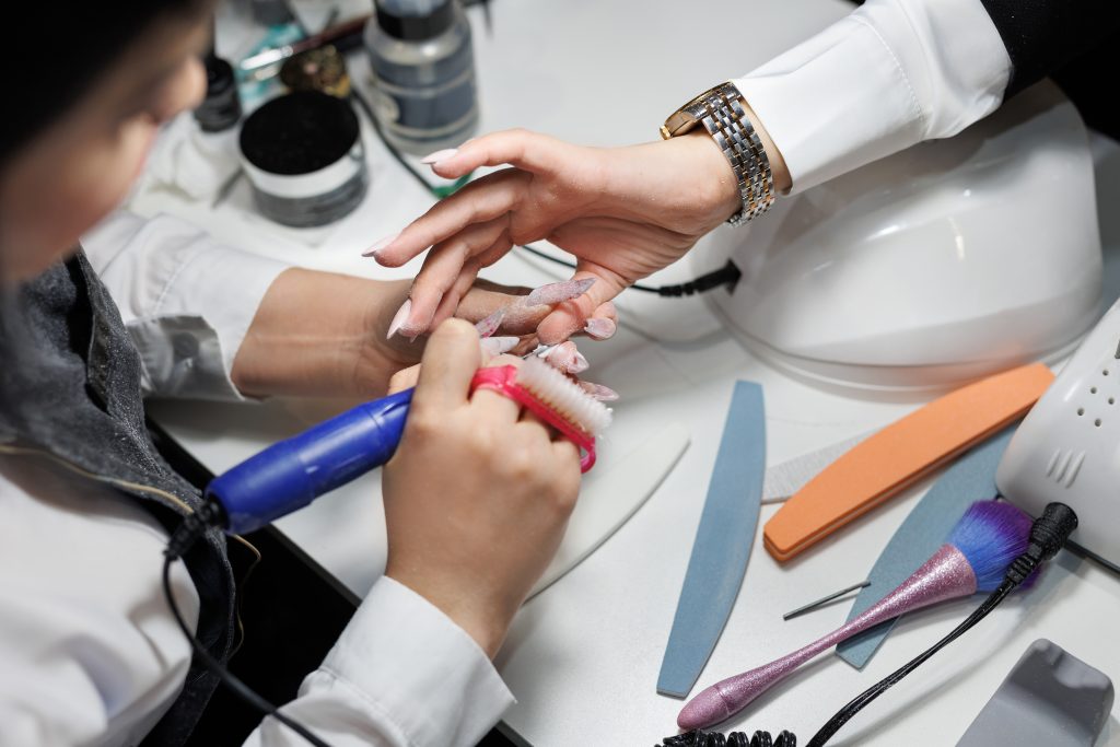 Manicure master who processes the surface of the nail with a cutter on an electric machine