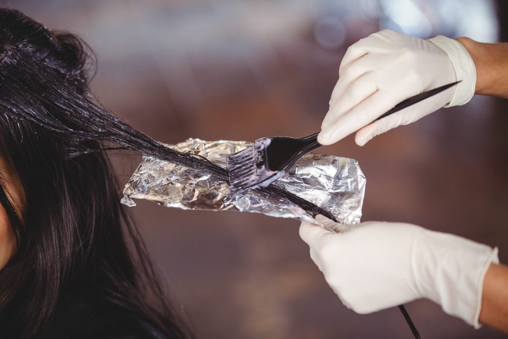 Hairdresser dyeing hair of her client at a salon