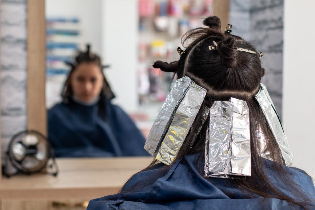 Woman in front of the hairdresser's mirror waiting for her hair treatment to continue.