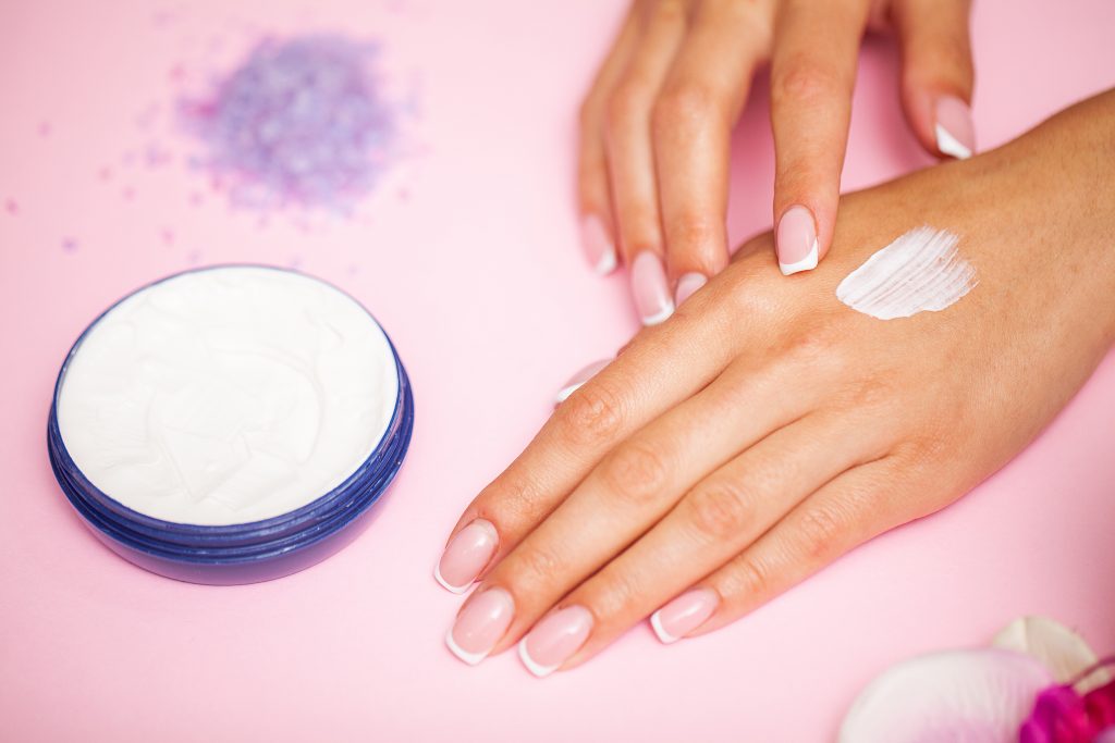 Woman applying hand cream at home, closeup.
