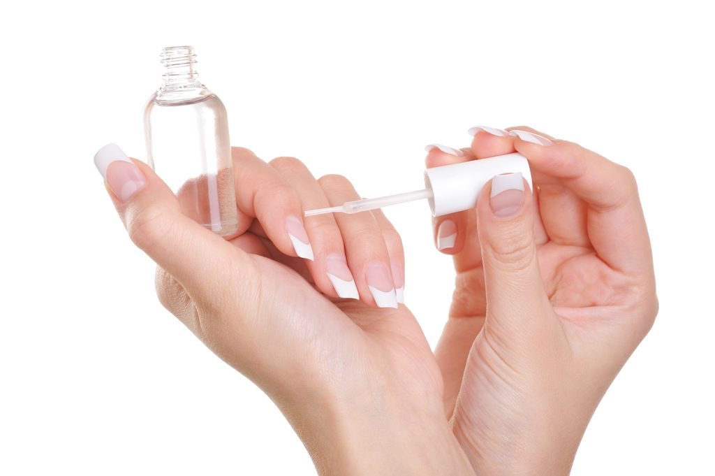Woman applying clear nail vanish on her fingernails - macro shot Strengthen Natural Nails.